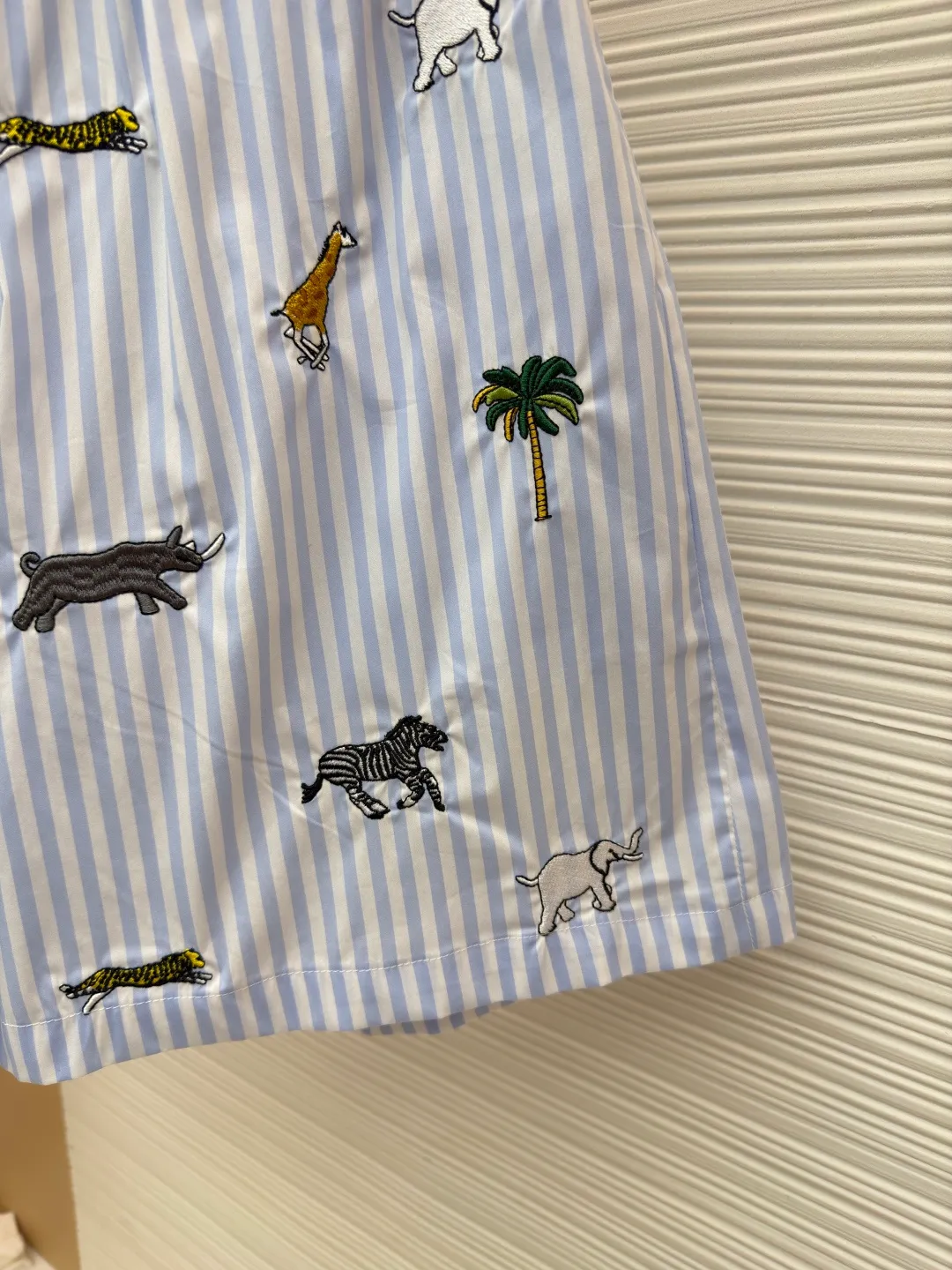 LOUIS VUITTON Animal and plant nostalgic style embroidered striped shorts ●Original version: purchased and developed by 14616 ●Item number: 1682542-A75 ●Fabric: cotton fabric ●Technology: embroidery production ●Color: blue ●Version: fitted version ●Weight: about 205 grams ●Size: S-M-L-XL ●Description: Made of high-count pure cotton poplin fabric. After pre-washing process, it feels smooth and breathable. It has both drape and stiffness, and is not easy to wrinkle and deform. The blue and white vertical stripes on the body are woven with yarn-dyed technology, and the texture is clear and does not fade. The animal and coconut tree patterns are presented with sophisticated embroidery technology. The embroidery threads are full of color and the stitches are dense. The patterns are three-dimensional and vivid, forming a rich visual hierarchy with the stripe base. The shirt has a Cuban collar style, with smooth necklines, custom mother-of-pearl buttons at the placket, and a warm texture. The overall shape is loose, the shoulder joints are straight and fine, the cuffs are cuffed with exquisite craftsmanship, custom accessories and three logos are complete, and the details are full of luxury craftsmanship. It is suitable for casual vacations and daily outings, etc. The overall wiring is straight and delicate, the fabric is comfortable and soft, and the color is consistent without color difference. It can be matched with the same style to create a fashionable look and control various occasions. Customized accessories, complete with three standards, same style for men and women!